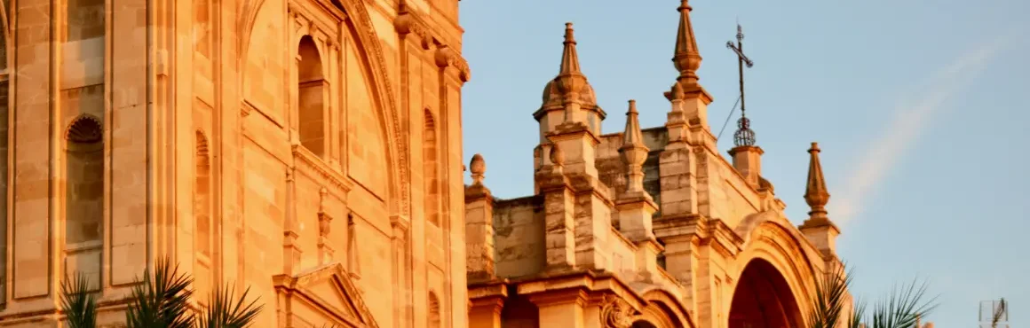 Facaden af Granadas katedral ved solnedgang over byen.